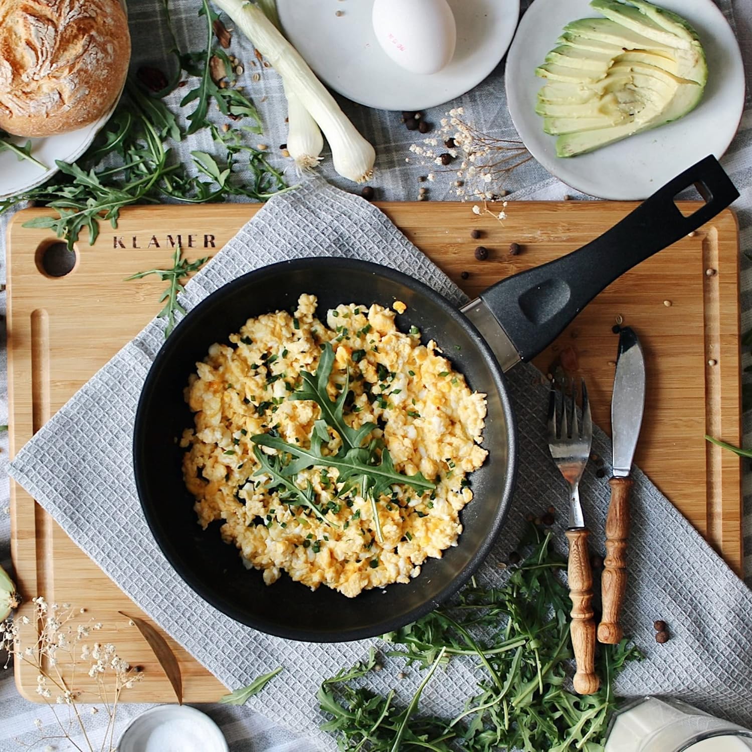 Profi Edelstahl-Bratpfanne 20cm with scrambled eggs and herbs on a wooden board.