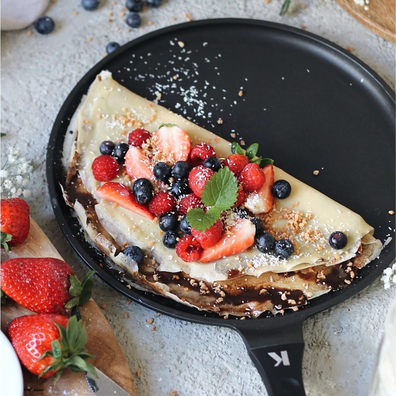 Crêpespfanne 28cm with a delicious crêpe topped with strawberries, blueberries, and raspberries on a grey surface.