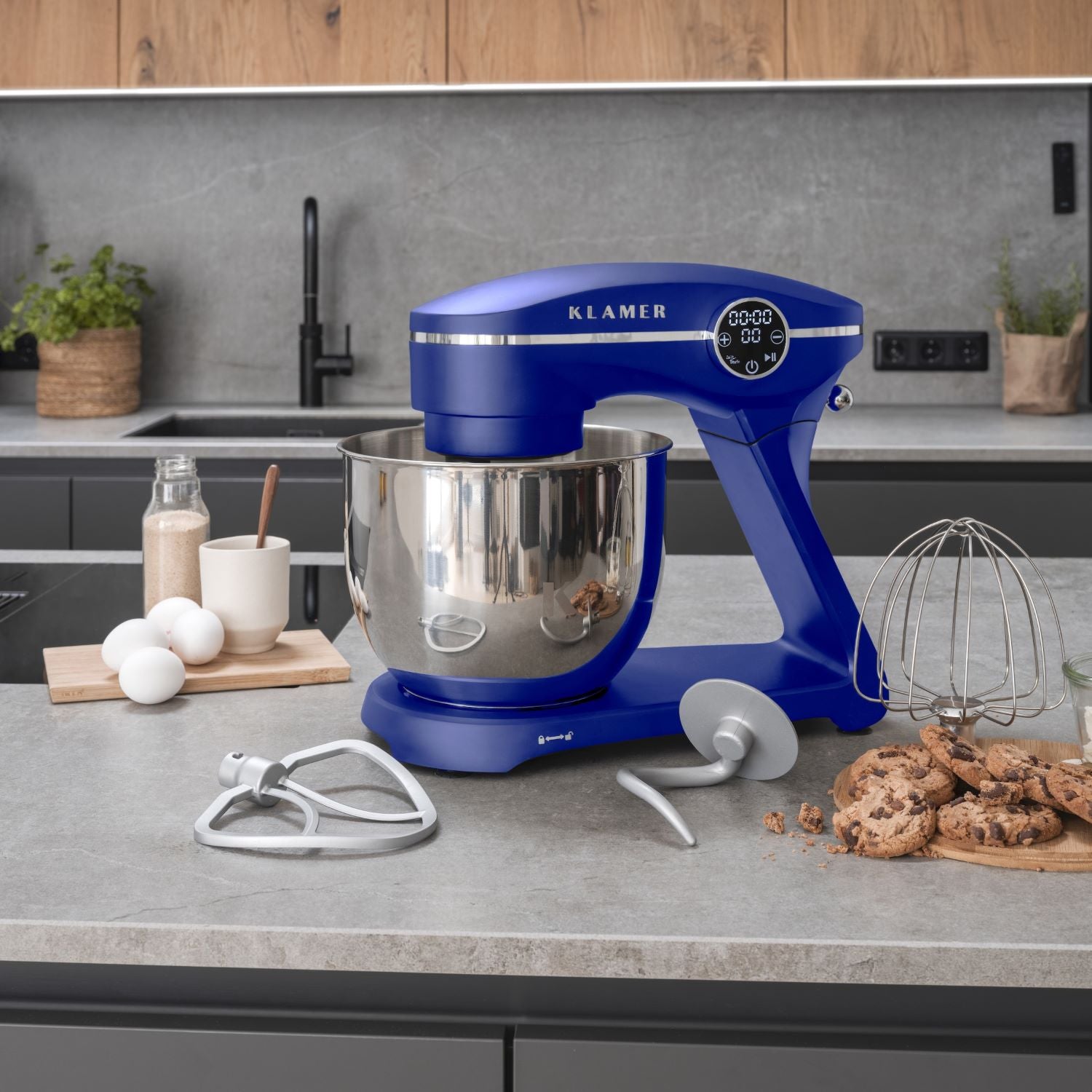 Küchenmaschine in Blau mit großem Edelstahlbehälter und Zubehör auf einer modernen Küchentheke.