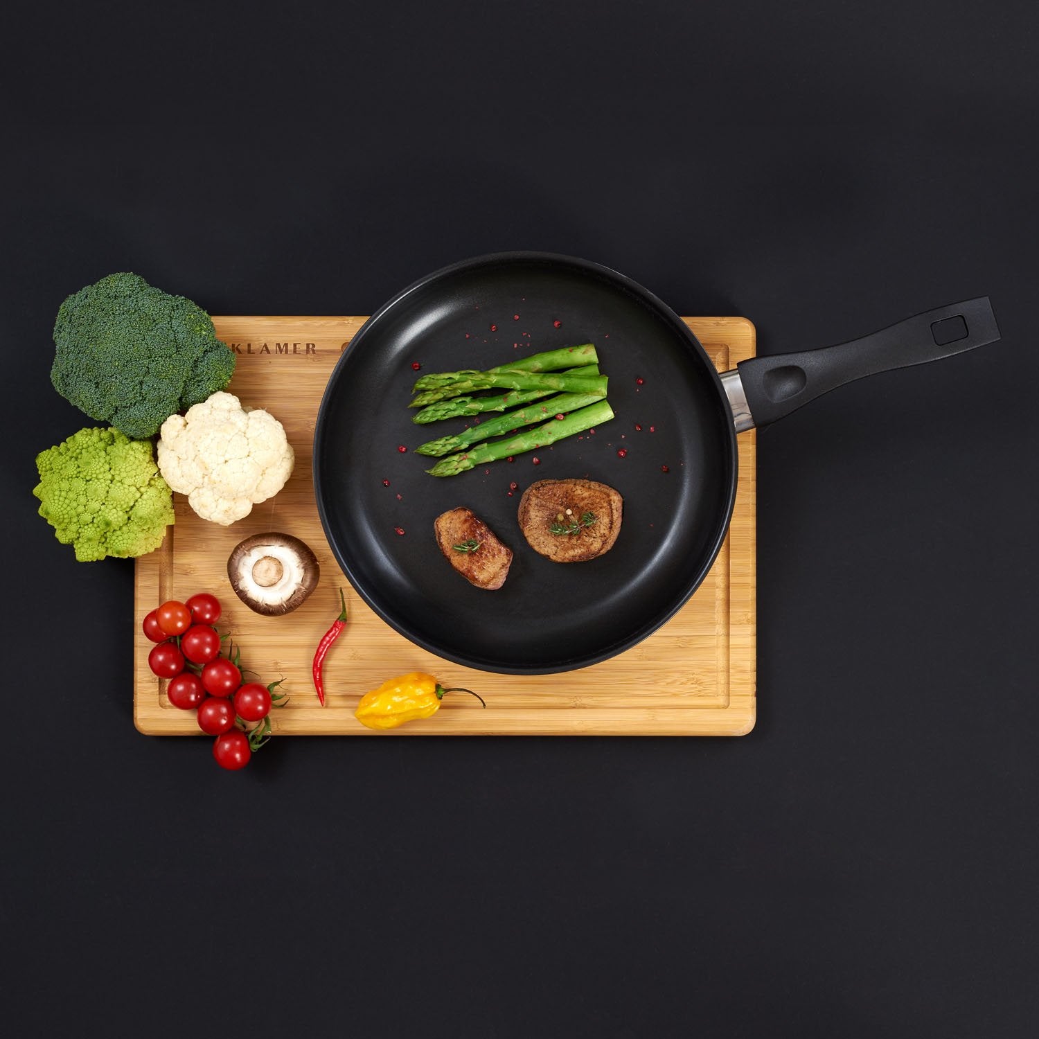Profi Edelstahl-Bratpfanne 20cm mit Gemüse und Fleisch auf einem Holzbrett arrangiert.