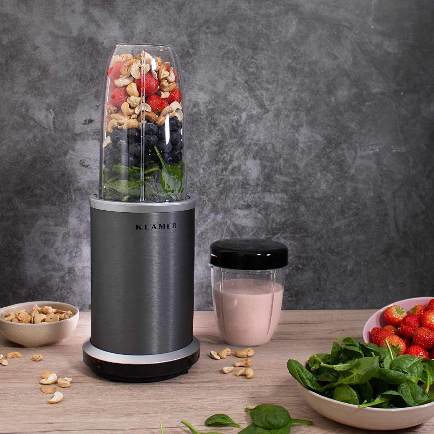 Bullet Mixer with fruits, nuts, and spinach for smoothie preparation on a kitchen counter.