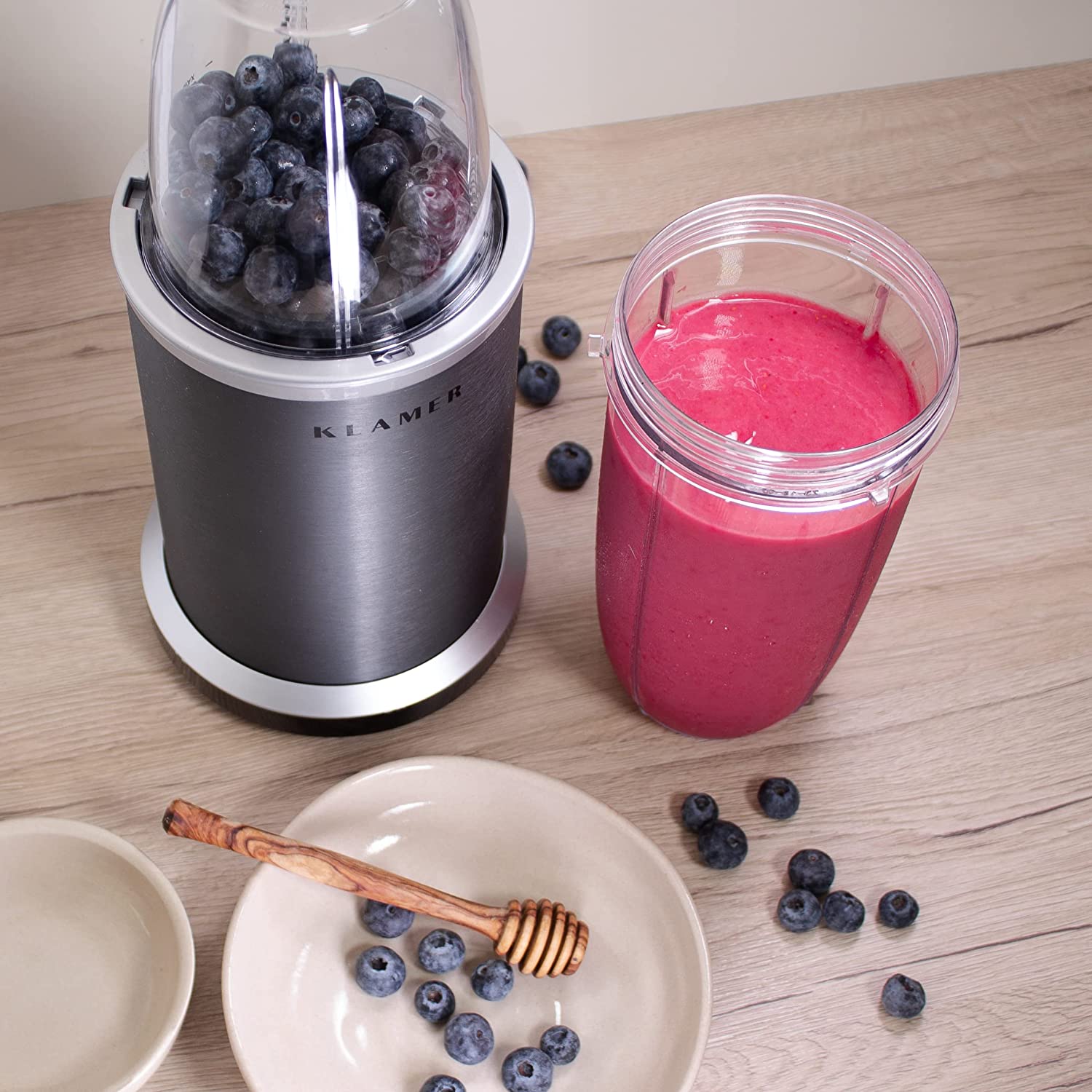 Bullet Mixer with blueberries and smoothie on a wooden table, showcasing versatility for mixing drinks and snacks.