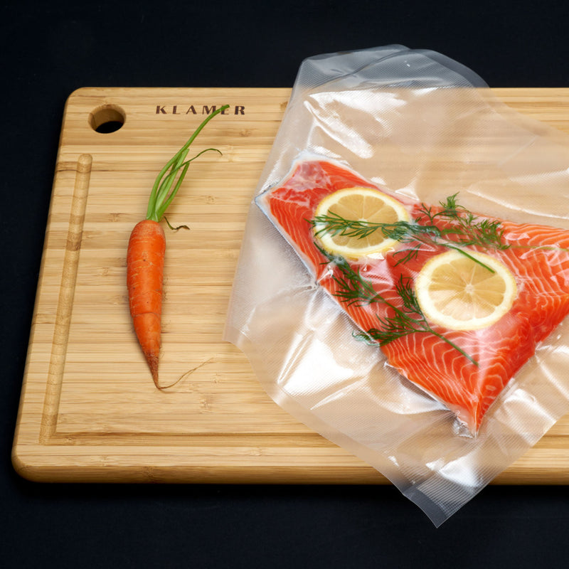 Vakuumierer Vacuum Pro 80: Sous Vide Lachs mit Zitrone und Dill, vakuumverpackt auf einem Holzschneider.