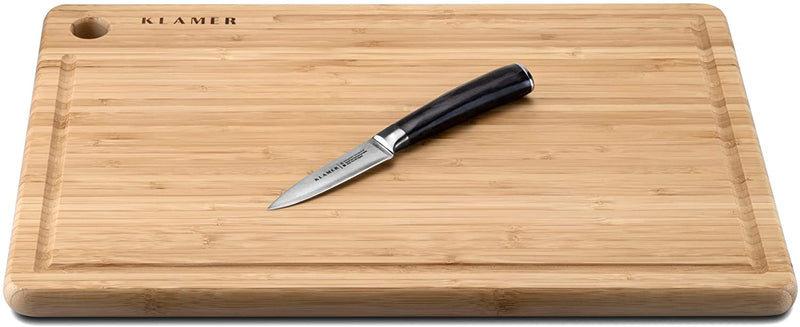 Damast Schälmesser 8.6cm on a wooden cutting board for versatile kitchen use.